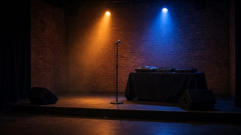 Empty brick-walled stage with a microphone stand and a DJ turntable setup under amber and blue stage lights.